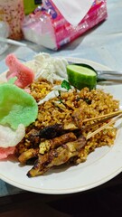 Savory Fried Rice Dish with Grilled Meat Skewers and Colorful Crackers on White Plate