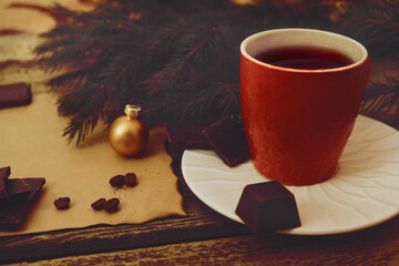 Christmas tree and decoration. Cup of aromatic coffee, Craft brown paper with burn marks and worn edges. Pieces of chocolate, sweet, coffee beans. Top view. Postcard. Greeting card, retro rustic style