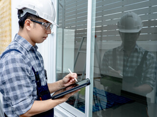Building inspector man in protective workwear using digital tablet app for site survey. Asian male...