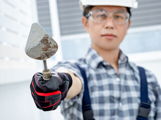 Plastering work tool. Asian man worker wearing protective safety helmet, goggles and gloves holding...