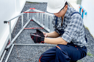 Asian man worker in safety workwear putting protective gloves in his hands at construction site....