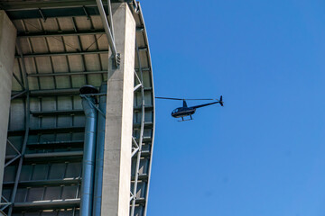 helicopter flying in the blue sky next to a modern industrial-style building with exposed...