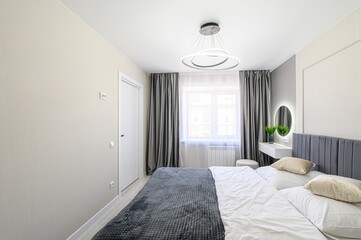 serene bedroom features a bed with gray velvet headboard, white linens, and a gray throw. Gray...