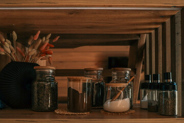 Close-up of a wooden kitchen shelf with glass jars filled with coffee, sugar, tea, and spices....