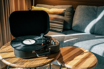 Turntable on a wooden coffee table in a cozy living room with soft lighting, striped pillow on a...