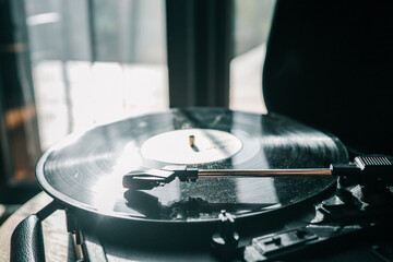 Close-up of a vinyl record spinning on a turntable in soft natural light, with a warm nostalgic...