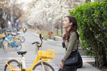 Woman enjoying view of white magnolia flowers on a tree branch in spring.