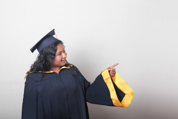 Young brunette Latina woman wearing a cap and gown celebrates her graduation and the completion of...
