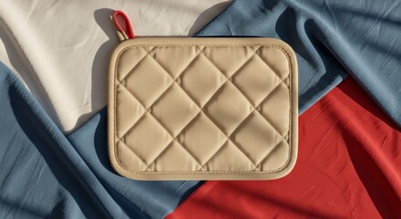 Blank pot holder laid flat on a soft, slightly wrinkled background of red, white, and blue fabric folds