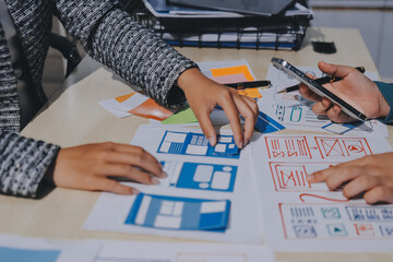 Group of young application developers analyzing uxui mobile app templates during a working meeting