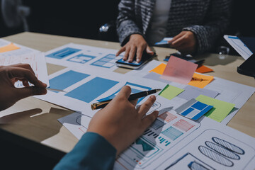 Group of young application developers analyzing uxui mobile app templates during a working meeting
