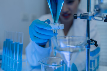 two scientists consult each other while conducting an experiment on a liquid substance in a...