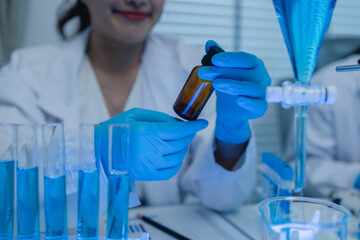 two scientists consult each other while conducting an experiment on a liquid substance in a...