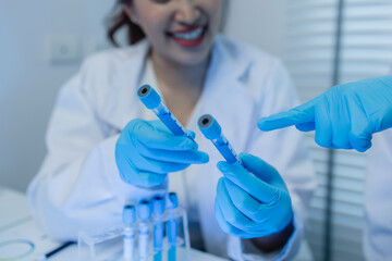 two scientists consult each other while conducting an experiment on a liquid substance in a...