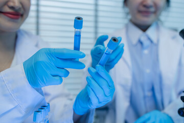 two scientists consult each other while conducting an experiment on a liquid substance in a...