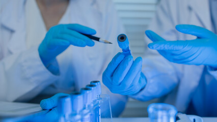 two scientists consult each other while conducting an experiment on a liquid substance in a...