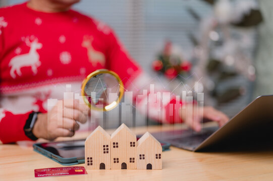 Detailed Festive Christmas Holiday Market Analysis Using Magnifying Glass Over Wooden Houses And Rising Line Graph, With Credit Card