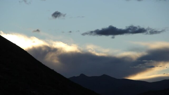 Timelapse of a sunset between mountains with clouds