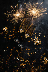 New Year 2026 greeting background with two champagne glasses and golden fireworks on a black surface. Top view layout  for holiday cards, banners, and celebratory designs.