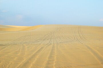 Vast Desert Landscape with Tire Tracks on Sand Under a Clear Sky. Mui Ne, Vietnam, White Dunes.