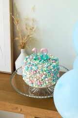 Celebratory 18th Birthday Cake with Colorful Sprinkles and Candles on a Glass Stand.
