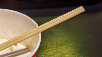 Empty bowl with disposable wooden chopsticks resting after a takeout meal