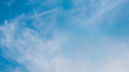 Vast ethereal sky with delicate wisps of white clouds gently diffused across the blue expanse