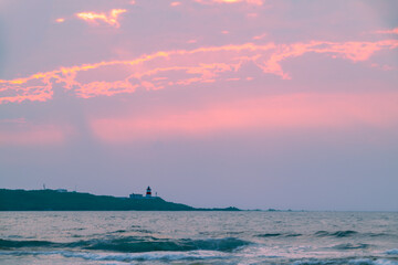 Fototapeta premium A breathtaking pink and purple sunset sky over the Fuguijiao Lighthouse and the Shimen coastline in New Taipei City, Taiwan, creating a serene and magical atmosphere.