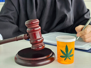 Courtroom setting displaying gavel and cannabis prescription container during legal