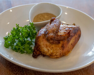 Half roasted chicken with parsley and sauce on a white plate