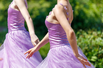 Two women in purple dresses are dancing in a field