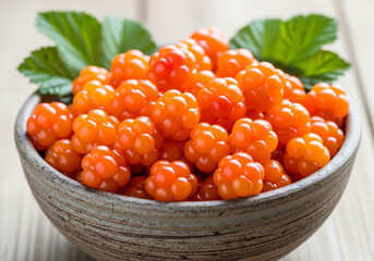 Bowl of fresh ripe cloudberries with green leaves