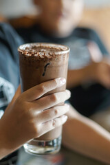 Hand holding a glass of ice chocolate drink