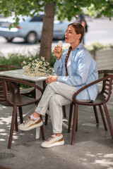 Icecream Woman Daisies: Woman enjoys ice cream at cafe table with daisies during daytime summer...