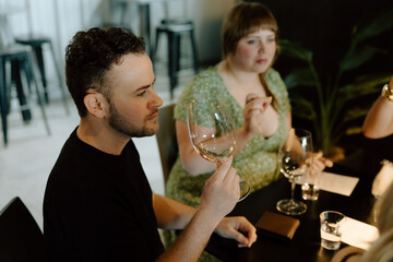 Sommelier smelling white wine during tasting with friends