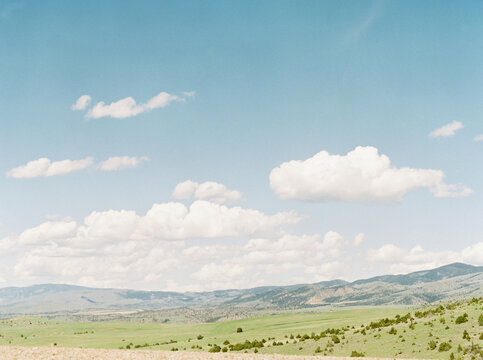 Rolling green hills beneath bright clouds and a clear blue sky