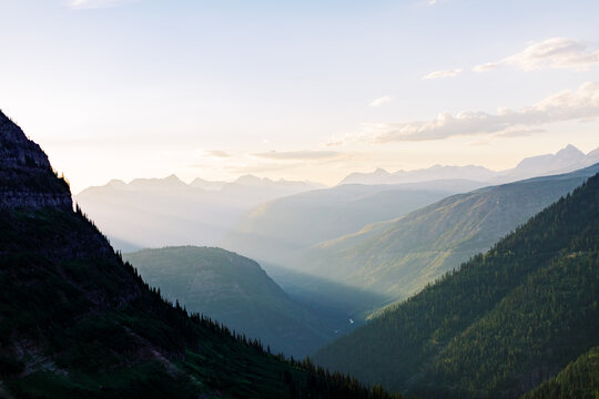 Soft evening light streams across layered mountains in Montana