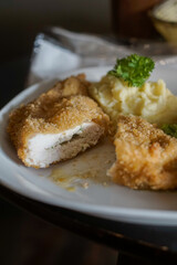 Chicken Kiev. Breaded and fried chicken fillets on a white plate, accompanied by creamy mashed potatoes garnished with fresh parsley.