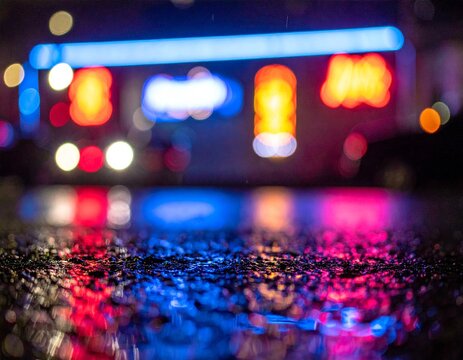 雨上がりのアスファルトに反射するネオンサイン、ボケ味