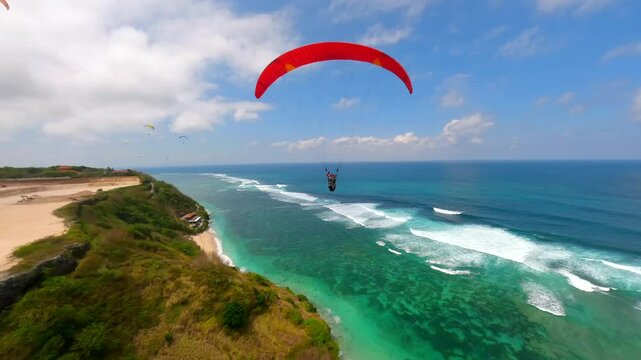 Cinematic FPV drone shot of paragliders gliding over cliffs and turquoise ocean at Pandawa Beach, Bali. Aerial view of dramatic coastline, tropical waves, and summer sky.