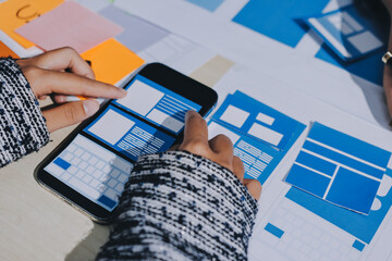 Group of young application developers analyzing uxui mobile app templates during a working meeting