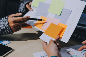 Group of young application developers analyzing uxui mobile app templates during a working meeting