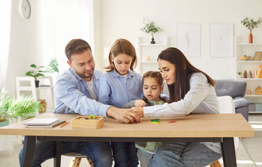Happy family fun, parents and cute little preschool kid girl, boy using developing learning board...