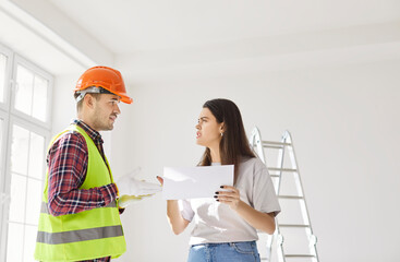 Foreman worker and serious female client asking, directs worker on meeting looking at project plan,...