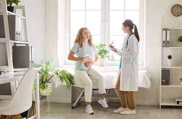 Female patient expresses stomach pain during a consultation with a doctor or nurse at a hospital....