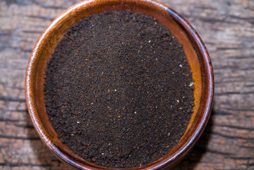 indian black tea, teaspoon with tea leaves on wooden table. Black tea powder in a wooden...