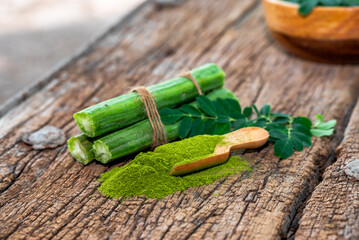 Moringa leaves in wooden bowl with Moringa powder on wooden background