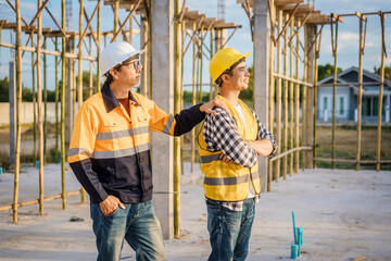 An elderly engineer and a middle-aged man at a construction site engage in a serious discussion one...