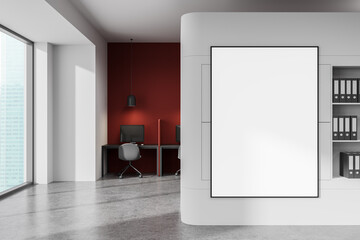 Blank vertical poster mockup on modern office wall with red accent background and workspace desks,...