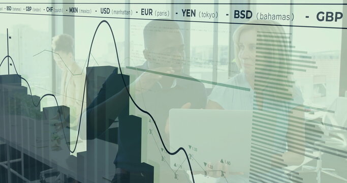 Collaborating colleagues in business attire reviewing laptop in office with charts on glass panels